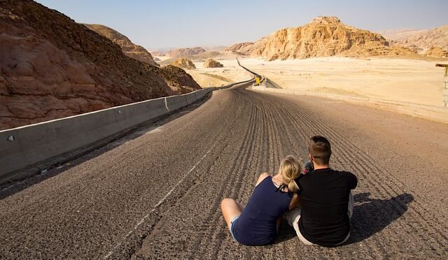 Imagem- casal sentados no meio da rodovia apreciando a paisagem